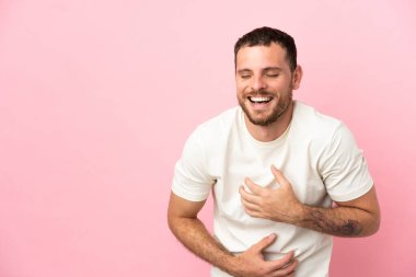 Pembe arka planda izole edilmiş genç Brezilyalı adam çok gülümsüyor.