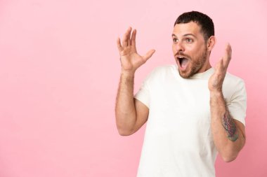 Pembe arka planda yalıtılmış Brezilyalı genç bir adam. Sürpriz bir yüz ifadesi var.