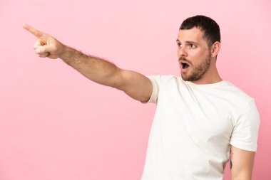 Pembe arka planda izole edilmiş genç Brezilyalı adam işaret ediyor