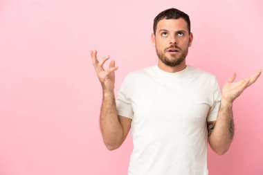 Pembe arka planda izole edilmiş genç Brezilyalı adam bunalımda.