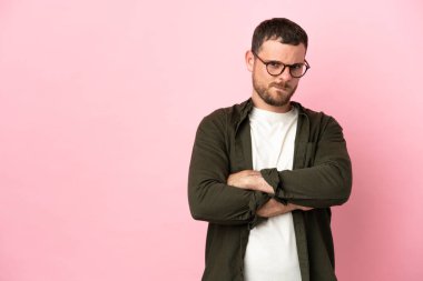 Pembe arka planda mutsuz bir ifadeyle izole edilmiş genç Brezilyalı adam.