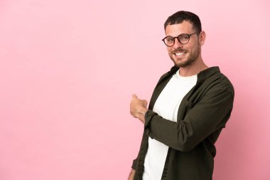 Pembe arka planda izole edilmiş genç Brezilyalı adam geriye işaret ediyor
