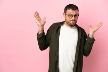 Pembe arka planda izole edilmiş genç Brezilyalı adam şüpheli hareketler yapıyor.