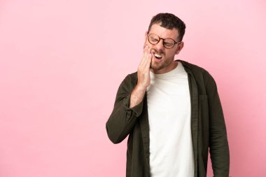 Pembe arka planda diş ağrısı çeken Brezilyalı genç bir adam.