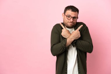 Pembe arka planda izole edilmiş genç Brezilyalı adam, yandakilerin şüphelerine işaret ediyor.