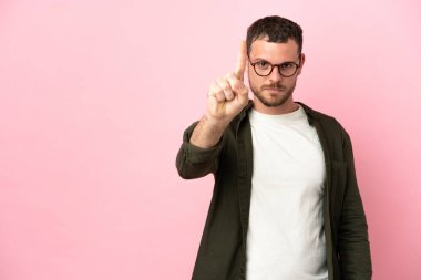 Pembe arka planda izole edilmiş genç Brezilyalı adam ciddi bir ifadeye sahip birini sayıyor