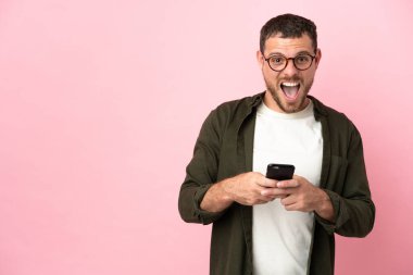 Pembe arka planda izole edilmiş genç Brezilyalı adam şaşırdı ve bir mesaj gönderiyor.