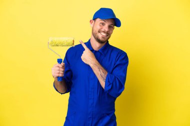 Ressam Brezilyalı adam sarı arka planda izole edilmiş bir ürün sunmak için yan tarafı işaret ediyor.
