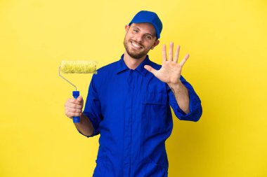 Ressam Brezilyalı adam sarı arka planda izole edilmiş, parmaklarıyla beşi sayıyor.