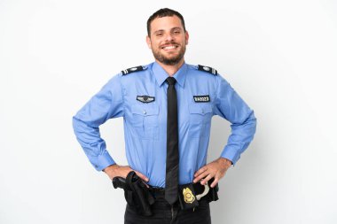 Genç Brezilyalı polis, beyaz arka planda izole edilmiş. Kolları kalçasında ve gülümsüyor.