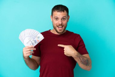 Genç Brezilyalı bir adam izole edilmiş geçmişinden çok fazla para alıyor ve şaşırmış yüz ifadesi var.