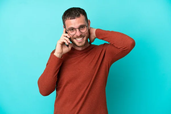 Joven Brasileño Usando Teléfono Móvil Aislado Sobre Fondo Azul Riendo — Foto de Stock