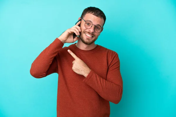 Young Brazilian Man Using Mobile Phone Isolated Blue Background Pointing — Stock Photo, Image