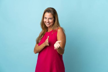 Orta yaşlı Brezilyalı bir kadın mavi arka planda izole edilmiş bir konferansta sunumdan sonra alkışlıyor.