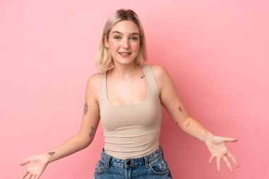 Pembe arka planda izole edilmiş genç beyaz kadın mutlu ve gülümsüyor.