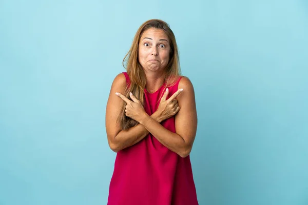 Middelbare Leeftijd Braziliaanse Vrouw Geïsoleerd Blauwe Achtergrond Wijzend Naar Lateralen — Stockfoto