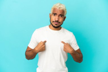 Genç Kolombiyalı yakışıklı adam mavi arka planda izole edilmiş kendini işaret ediyor.
