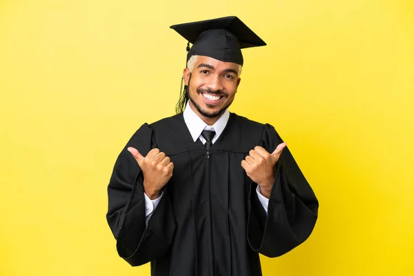 Joven Graduado Universitario Colombiano Aislado Sobre Fondo Amarillo Con Pulgares —  Fotos de Stock