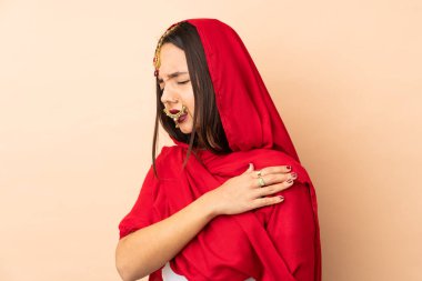 Genç Hintli kadın bej arka planda izole edilmiş, omuz ağrısından muzdarip, çabaladığı için