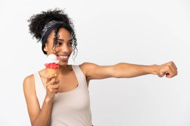 Beyaz arka planda izole edilmiş kornet dondurması olan Afro-Amerikalı genç bir kadın baş parmak hareketi yapıyor.