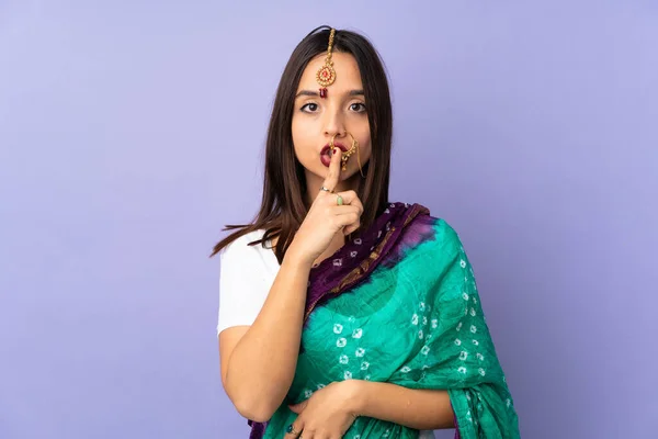 紫色の背景に孤立した若いインド人女性が口の中に指を入れて沈黙のジェスチャーの兆候を示す — ストック写真