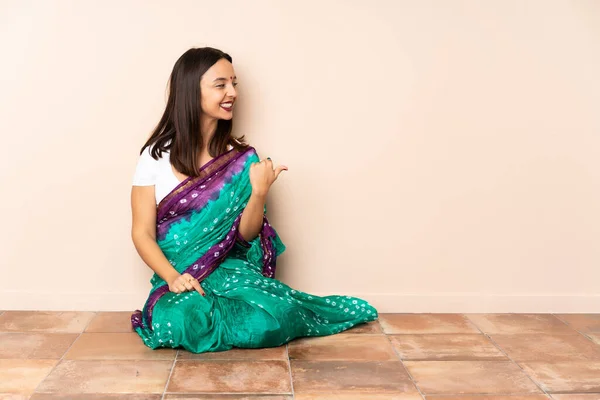 Young Indian Woman Sitting Floor Pointing Side Present Product — Stock Photo, Image