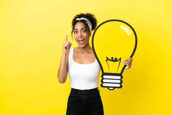 Young African American Woman Isolated Yellow Background Holding Bulb Icon — Stock Photo, Image