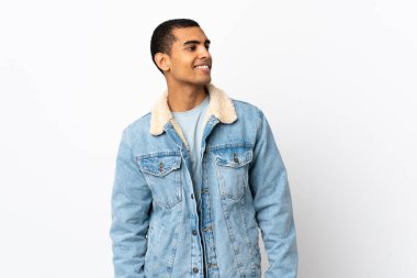 Afro-Amerikalı bir adam izole edilmiş beyaz arka planda, yana bakıyor ve gülümsüyor.