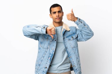 İzole edilmiş beyaz arka plan üzerinde afro-amerikan adam iyiye-kötüye işaret yapıyor. Evet ya da hayır arasında kararsız