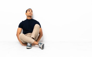 Afro-Amerikalı bir adam yerde oturuyor ve yukarı bakıyor.