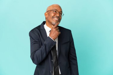 İşletme son sınıf öğrencisi mavi arka planda izole edilmiş, yana bakıyor ve gülümsüyor.