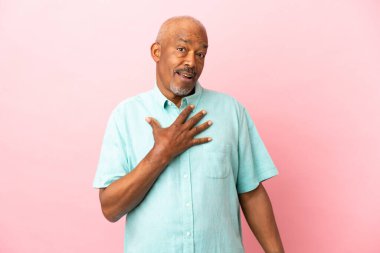 Kübalı son sınıf öğrencisi pembe arka planda izole edilmiş.