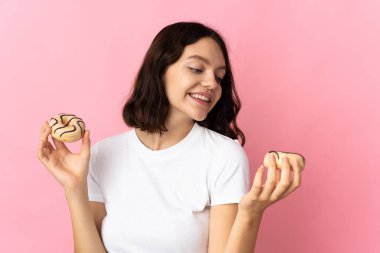 Genç Ukraynalı kız pembe arka planda izole edilmiş elinde mutlu bir ifadeyle çörek tutuyor.