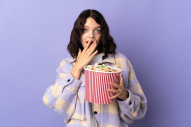 Mor arka planda izole edilmiş genç Ukraynalı kız elinde koca bir kova patlamış mısır tutuyor.