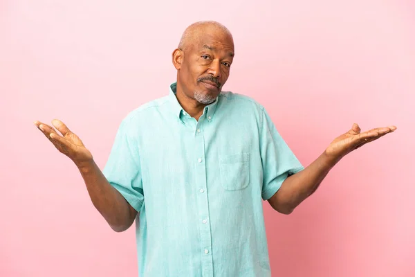 Cuban Senior Isolated Pink Background Having Doubts While Raising Hands — Stock Photo, Image