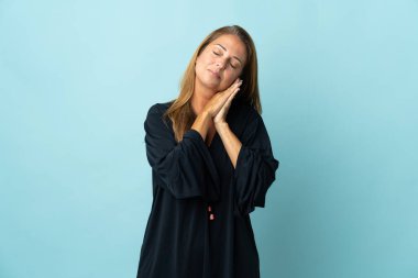 Mavi arka planda izole edilmiş orta yaşlı Brezilyalı bir kadın uyku jesti yapıyor.