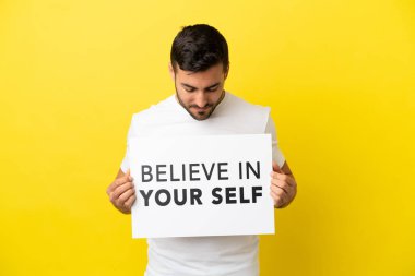 Sarı arka planda izole edilmiş yakışıklı beyaz bir adam. Elinde 