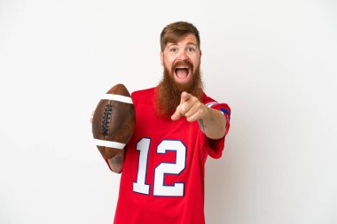 Beyaz arka planda ragbi oynayan Kafkasyalı genç adam şaşırmış ve ön tarafı işaret ediyor.