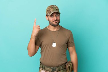 Mavi arka planda izole edilmiş künyeli ordu işaret parmağıyla işaret etmek harika bir fikir.