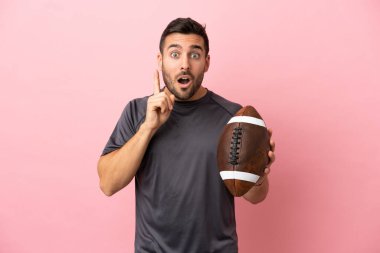 Pembe arka planda ragbi oynayan beyaz bir adam çözümü bulmak için parmağını kaldırıyor.