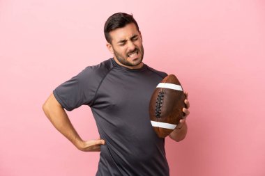 Pembe arka planda ragbi oynayan beyaz bir adam gayret gösterdiği için sırt ağrısından muzdarip.