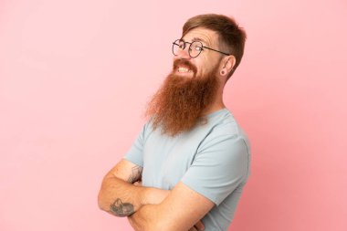 Pembe arka planda izole edilmiş, kolları bağlı ve mutlu genç beyaz bir adam.