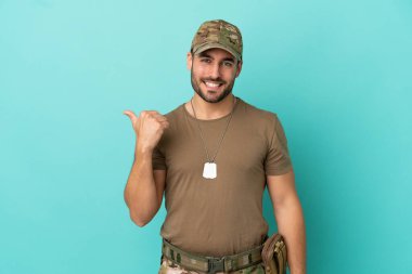 Mavi arka planda izole edilmiş künyesi olan ordu bir ürünü sunmak için kenarı işaret ediyor.