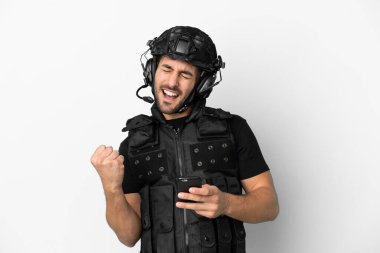 Beyaz arka planda izole genç Kafkas SWAT zafer pozisyonunda telefon ile