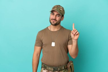 Mavi arka planda izole edilmiş künyesi olan ordu en iyinin işareti olarak parmağını kaldırıyor.