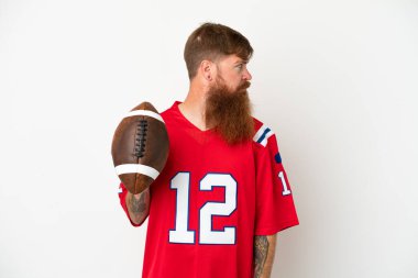 Beyaz arka planda izole edilmiş, ragbi oynayan Kafkasyalı genç adam yan tarafa bakıyor.