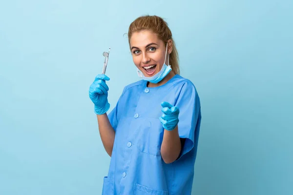 Mladá Žena Zubař Drží Nástroje Přes Izolované Modré Pozadí Ukazuje — Stock fotografie