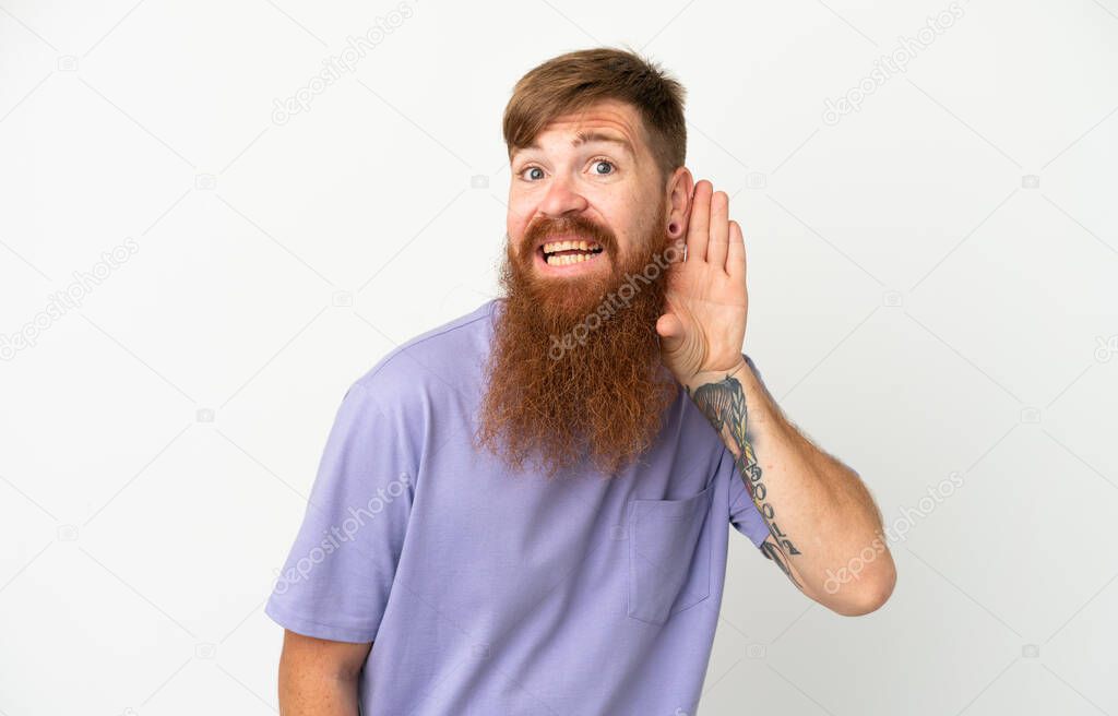 Young reddish caucasian man isolated on white background listening to something by putting hand on the ear