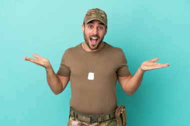 Mavi arka planda izole edilmiş künyeli asker, şok olmuş yüz ifadesi var.