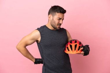 Pembe arka planda izole edilmiş genç bir bisikletçi gayret gösterdiği için sırt ağrısı çekiyor.